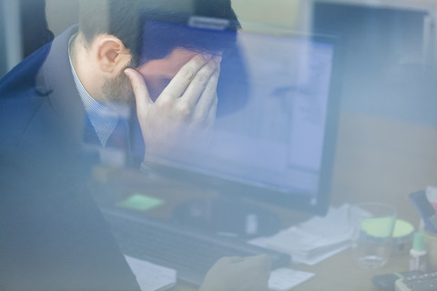 Young businessman in office with head in hand stock photo