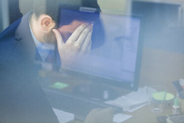 Junger Geschäftsmann im Büro mit Kopf in der Hand - ZEDF00455