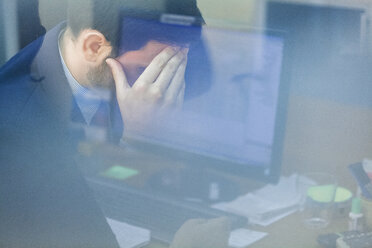 Young businessman in office with head in hand - ZEDF00455