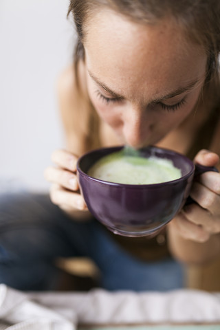 Frau trinkt Matcha Latte zu Hause, lizenzfreies Stockfoto