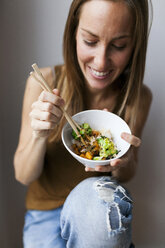 Frau zu Hause isst Gemüse mit Stäbchen - VABF00899