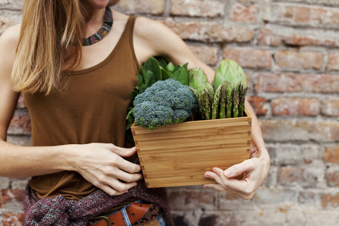 Woman holding basket with fresh vegetables stock photo