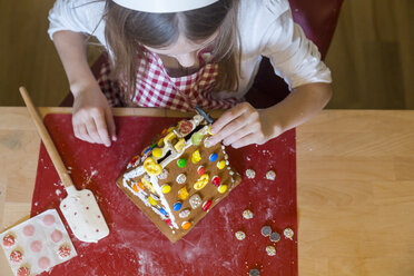 Mädchen, das ein Lebkuchenhaus garniert, Ansicht von oben - SARF03090