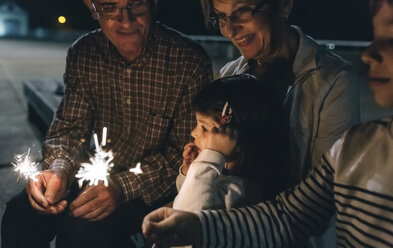 Grandparents with grandchildren holding sparklers at night - DAPF00527