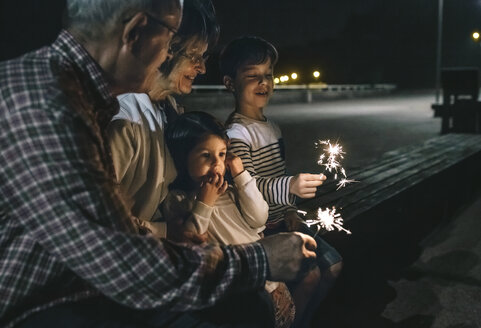 Großeltern mit Enkelkindern, die nachts Wunderkerzen halten - DAPF00528