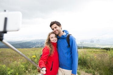 Young couple on a hiking tour taking a selfie with selfie stick - HAPF01195