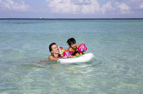 Malediven, Gulhi, Mutter und Tochter spielen mit einer aufblasbaren Luftmatratze im seichten Wasser - DSGF01252