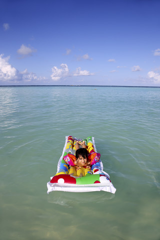 Malediven, Gulhi, Mädchen schwimmt auf aufblasbarer Luftmatratze im Wasser, lizenzfreies Stockfoto