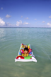 Malediven, Gulhi, Mädchen schwimmt auf aufblasbarer Luftmatratze im Wasser - DSGF01254