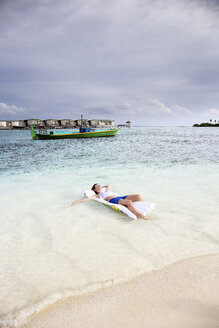 Malediven, Guraidhoo, Frau treibt auf Luftmatratze in flachem Wasser - DSGF01263