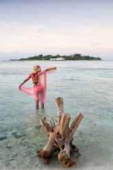 Malediven, Guraidhoo, Frau im seichten Wasser bei Sonnenuntergang stehend - DSGF01265