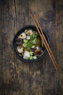 Schale Miso-Suppe mit Bio-Tofu, Shitake-Pilzen, Lauch und Petersilie auf dunklem Holz - LVF05697