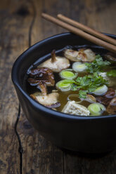 Bowl of miso soup with organic tofu, shitake mushrooms, leek and parsley on dark wood - LVF05698