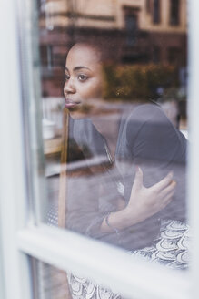 Junge Frau in einem Café schaut aus dem Fenster - UUF09487