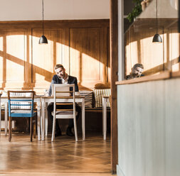 Junger Geschäftsmann arbeitet in einem Cafe - UUF09517