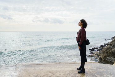 Frau steht vor dem Meer und schaut in die Ferne - KKAF00165