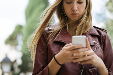 Junge Frau schaut auf ihr Mobiltelefon - KKAF00170