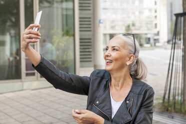 Lächelnde reife Frau nimmt Selfie mit Smartphone - JUNF00724