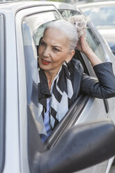 Portrait of businesswoman leaning out of car window - JUNF00739
