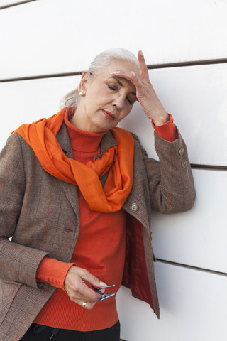 Portrait of fashionable mature woman with eyes closed leaning against white wall stock photo