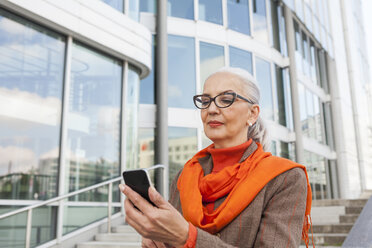 Portrait of fashionable mature woman looking at cell phone - JUNF00749