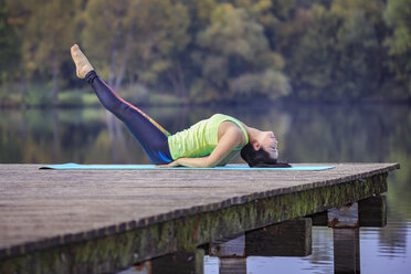 Frau übt Yoga auf einem Steg an einem See - VTF00568