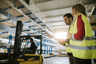 Man and woman wearing reflective vests in warehouse - ZEDF00468