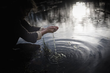 Frau hockt am Ufer und schöpft Wasser - MJF02118