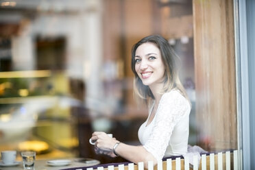 Young woman sitting in coffee shop, drinking coffee - TAMF00890
