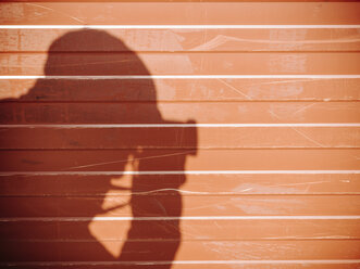 Schatten eines Mannes, der mit einer Kamera an einer Wand fotografiert - KRPF02070