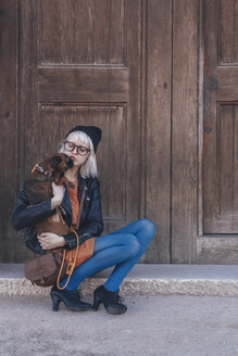 Young woman holding dog outdoors - RTBF00555