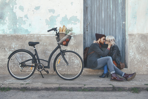 Young couple in love kissing on door step next to a bike stock photo