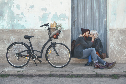 Junges verliebtes Paar küsst sich auf der Türschwelle neben einem Fahrrad - RTBF00559