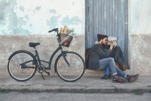 Young couple in love kissing on door step next to a bike - RTBF00559