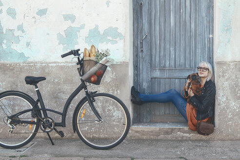 Young woman sitting in door frame holding dog - RTBF00562