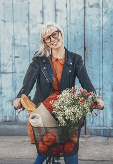 Smiling young woman with groceries on bicycle - RTBF00563