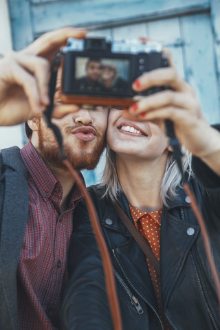 Junges Paar macht ein Selfie mit einer alten Kamera, lizenzfreies Stockfoto