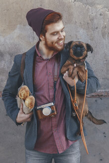 Smiling young man holding dog - RTBF00569