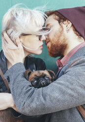Junges verliebtes Paar küsst sich mit Hund zwischen ihnen - RTBF00573