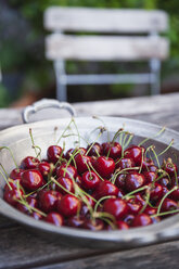 Zinc bowl of sweet cherries on garden table - GWF04919