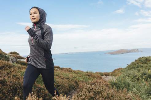 Ireland, Howth, woman running on coastal path - MADF01300