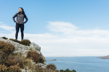 Irland, Howth, weibliche Athletin an der Steilküste stehend - MADF01302
