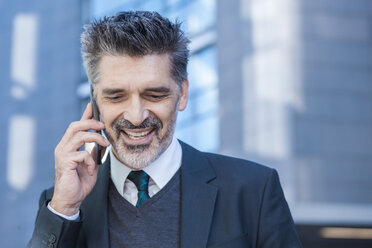 Lächelnder Geschäftsmann im Freien mit Mobiltelefon - TCF05218