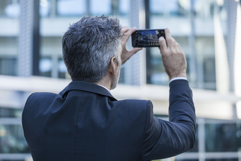 Geschäftsmann im Freien, der ein Handyfoto macht, lizenzfreies Stockfoto