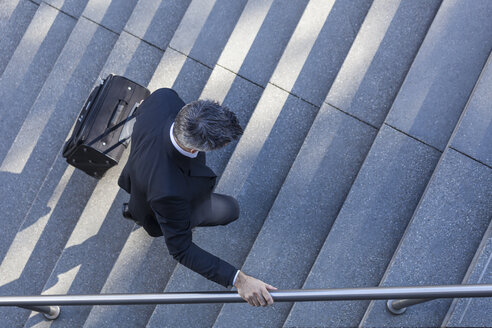 Businessman walking with suitcase on stairs - TCF05226