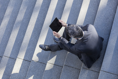 Geschäftsmann im Freien auf der Treppe sitzend mit Tablet, lizenzfreies Stockfoto