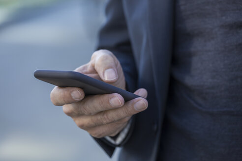 Nahaufnahme eines Geschäftsmannes im Freien, der ein Mobiltelefon hält - TCF05234