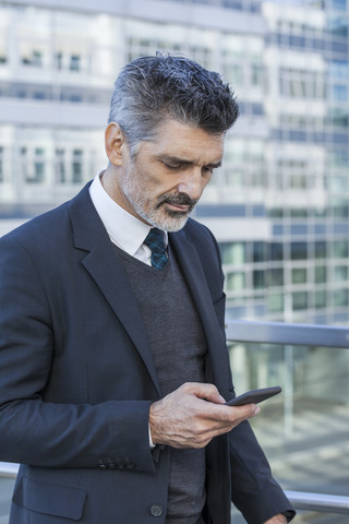 Businessman outdoors looking on cell phone stock photo