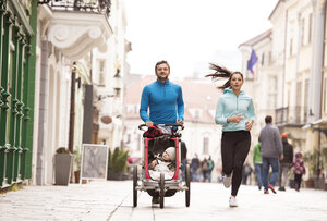 Eltern laufen mit Kind im Kinderwagen in der Stadt - HAPF01208