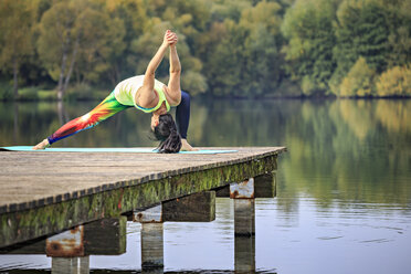 Frau übt Yoga auf einem Steg an einem See - VTF00575